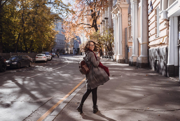Portrait of beautiful brunette girl walking down the street. Smiling. Urban city scene. Warm sunny weather. Outdoors - Fotó, kép