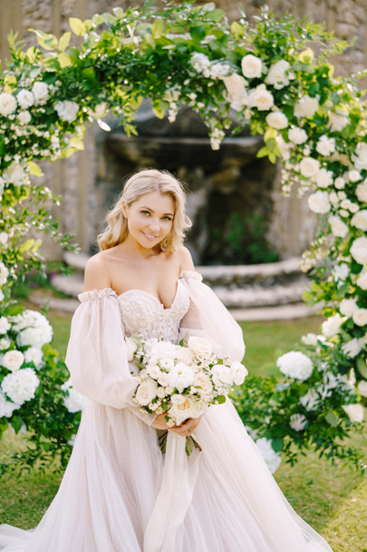 Wedding at an old winery villa in Tuscany, Italy. Portrait of a bride near a round arch of flowers. The scenery for the wedding ceremony. - Photo, Image
