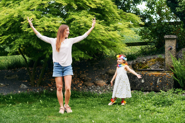 Young mother dancing with cute little daughter in garden, family spending time together - Fotoğraf, Görsel