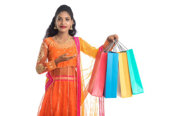 Beautiful Indian young girl holding shopping bags while wearing traditional ethnic wear. Isolated on a white background - Foto, imagen