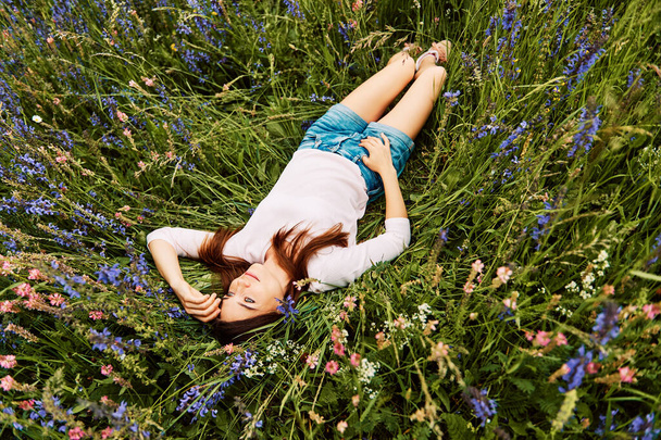 Młoda kobieta leży w polu, cieszyć się miły dzień, jedność z naturą - Zdjęcie, obraz