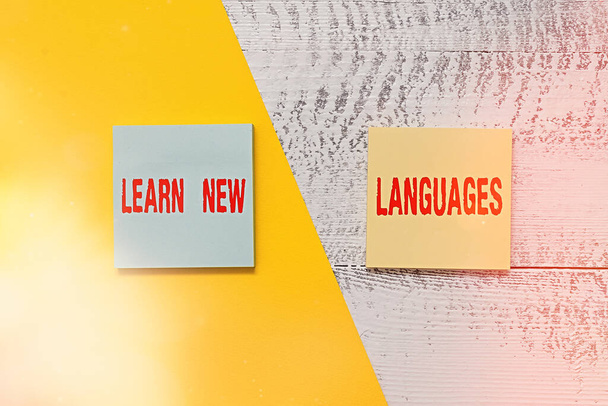 Text sign showing Learn New Languages. Conceptual photo developing ability to communicate in foreign lang Two multicolor blank notepads colored paper sheet retro wooden background. - Photo, Image