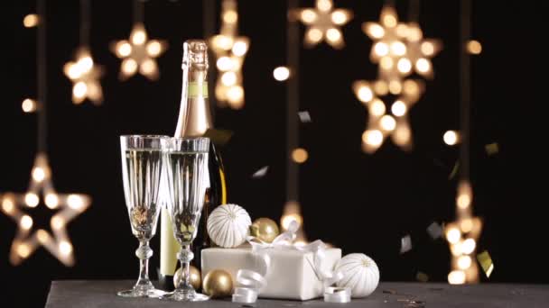 Confetti spada na stół z szampanem, prezentem świątecznym i wystrojem - Materiał filmowy, wideo