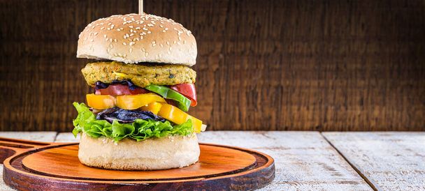 veganistische maaltijd, vleesloze hamburger, glutenvrij, gemaakt met verschillende groenten en eiwitten. Bruin brood op gourmet hamburger, rustieke achtergrond. - Foto, afbeelding