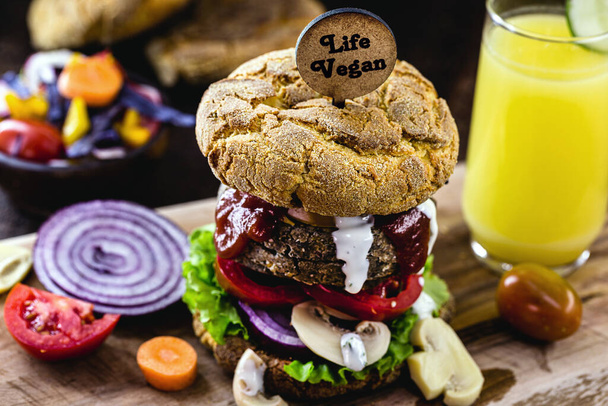 gastronomische veganistische snack, vleesloze hamburger, met klein bord geschreven in het Engels Veganistisch leven. Glutenvrije maaltijd, bereid met verschillende groenten en eiwitten. - Foto, afbeelding