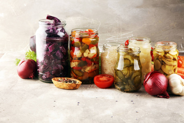Säilyttää vihanneksia lasipurkeissa. Kurkkua, porkkanaa, käymistietä kaalia ja sipulia maalaispöydällä
 - Valokuva, kuva
