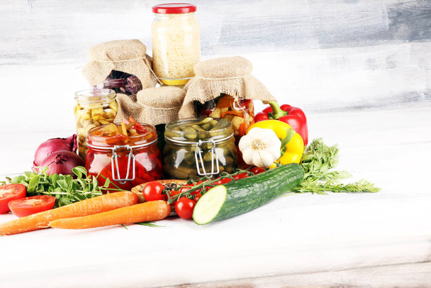 Conserva le verdure in barattoli di vetro. Cetriolo sottaceto, carota, cavolo fermentato e cipolle su tavolo rustico
 - Foto, immagini