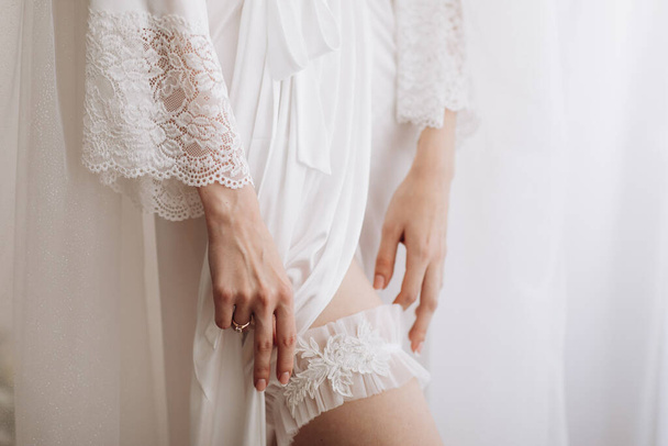 Menyasszonyok reggele. Gyönyörű fiatal nő menyasszony fehér selyem köntösben és fehérneműben. Esküvő és menyasszony koncepció. - Fotó, kép