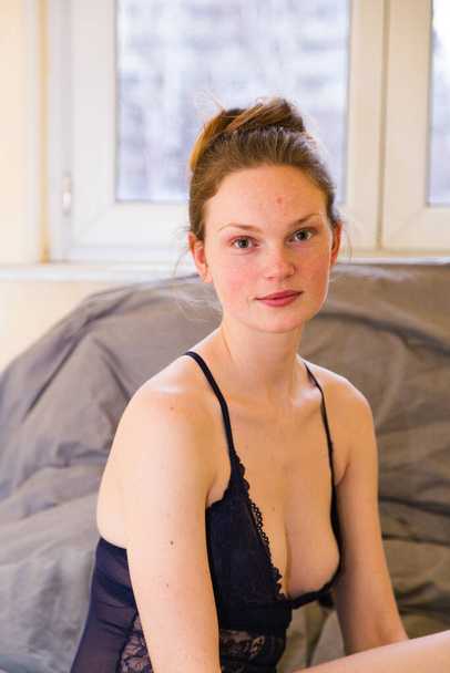 Seductive woman sits in bed in blue body suit - Fotoğraf, Görsel