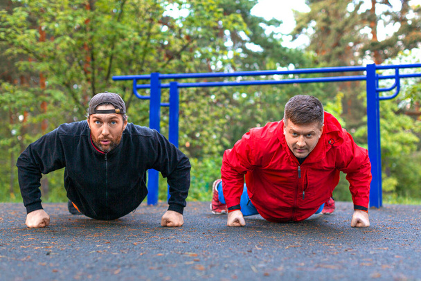 Two middle aged athletes doing push ups. - Photo, Image
