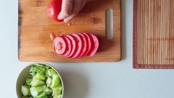 Bovenaanzicht van een mannelijke handen citerend tomaat voor salade. - Video