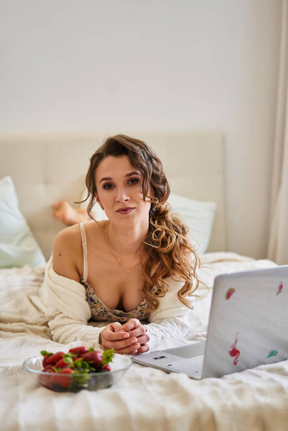  Beautiful girl at home in bed with white sheets at the computer - Foto, imagen