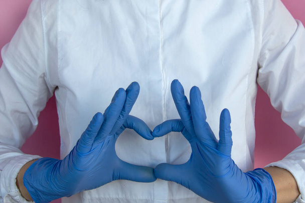 Dziewczyna w lateksowych rękawiczkach pokazuje kształt serca. Kochamy naszych lekarzy.. - Zdjęcie, obraz