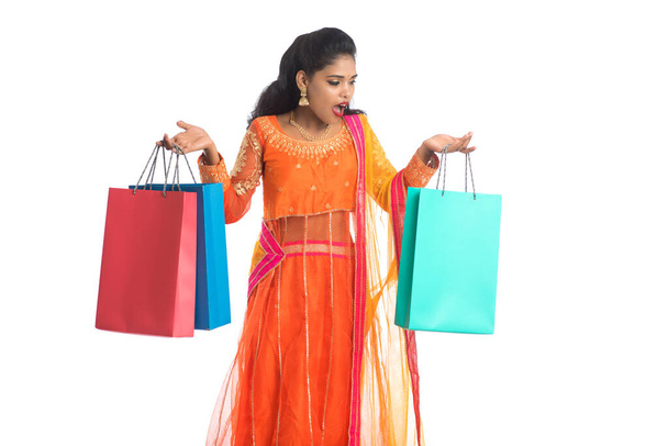 Beautiful Indian young girl holding shopping bags while wearing traditional ethnic wear. Isolated on a white background - Valokuva, kuva