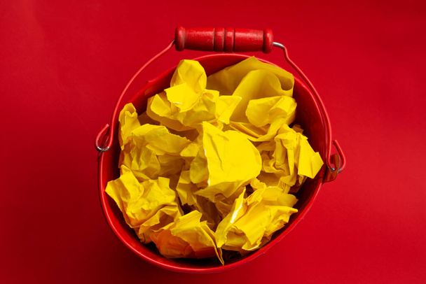 cubo de metal rojo con papel amarillo arrugado.Concepto de crisis de creatividad
 - Foto, Imagen