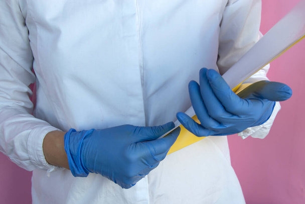 Une fille en gants bleu latex tient un dossier pour les documents dans ses mains
 - Photo, image