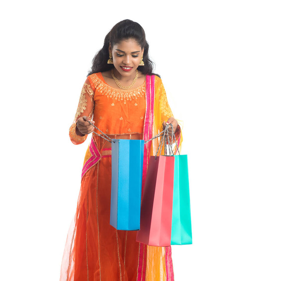 Beautiful Indian young girl holding shopping bags while wearing traditional ethnic wear. Isolated on a white background - Foto, Imagem