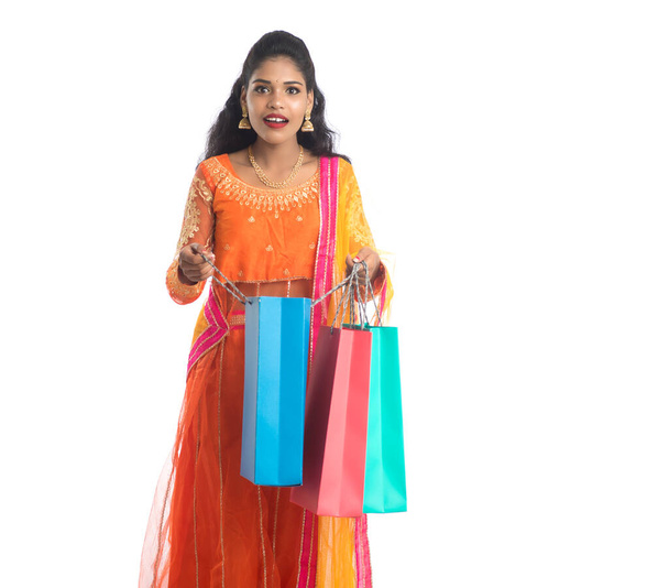Beautiful Indian young girl holding shopping bags while wearing traditional ethnic wear. Isolated on a white background - 写真・画像