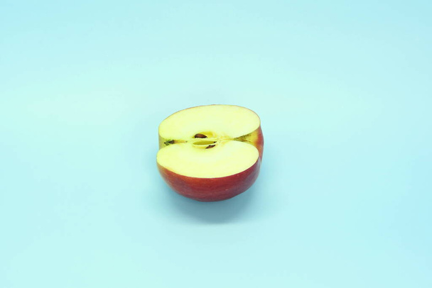 Half a juicy fresh apple on a blue background. Delicious sliced fruit - Фото, зображення