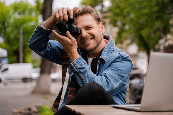 Fotograaf hipster reiziger schieten buiten in het centrum van de stad park, glimlachen en gelukkig voelen, freelancer werken online en hebben een shoot voor foto voorraad. Gebruik laptopcomputer voor sleutelwoorden - Foto, afbeelding