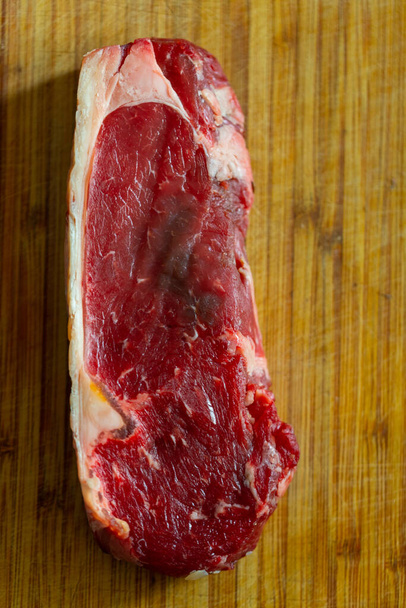 Shots  of a sliced raw fresh rump steak with fat on the steak on a wooden board - Photo, Image