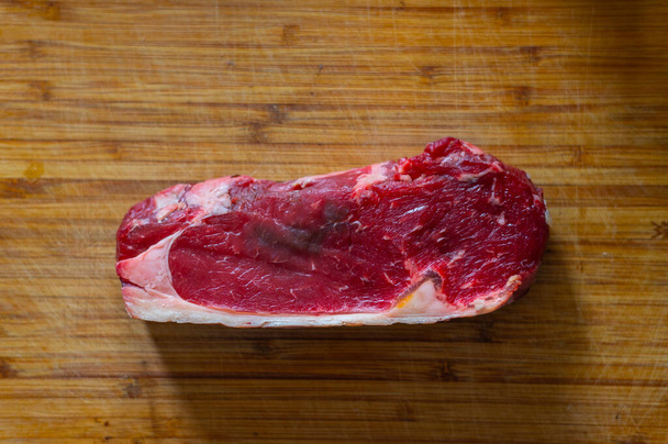 Aufnahmen eines in Scheiben geschnittenen frischen Rumpsteaks mit Fett auf dem Steak auf einem Holzbrett - Foto, Bild