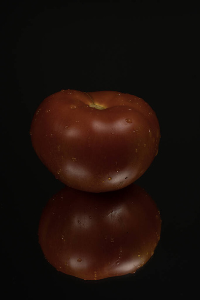 Pomidor na czarnym refleksyjnym tle studia. Odizolowane czarne, błyszczące lustro lustrzane tło dla każdej koncepcji. - Zdjęcie, obraz