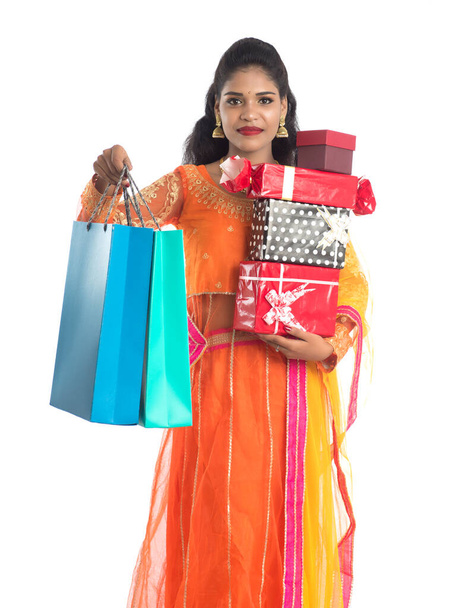 Beautiful woman carrying many shopping bags and gift Box on a white background. - Фото, изображение