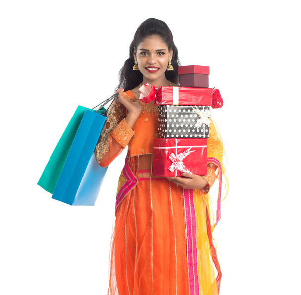 Beautiful woman carrying many shopping bags and gift Box on a white background. - Фото, изображение
