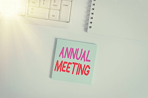 Handwriting text writing Annual Meeting. Concept meaning yearly meeting of the general membership of an organization Empty note paper on the white background by the pc keyboard with copy space. - Photo, Image