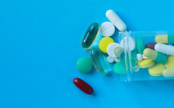 Assorted pills and capsules, a bottle on a blue background. Pharmaceutical medicine. Copy space for text. - Фото, зображення