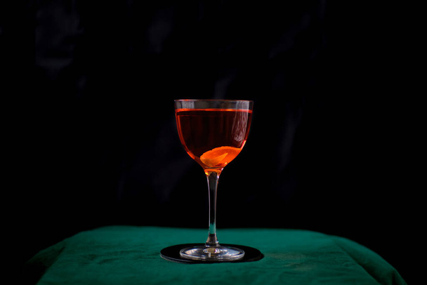 Roter Cocktail in Nick- und Nora-Glas auf schwarzem Hintergrund - Foto, Bild