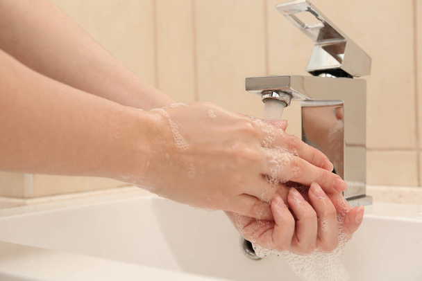 Woman washing hands with antiseptic soap in bathroom, closeup - Zdjęcie, obraz