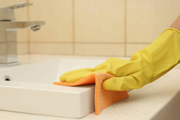 Woman cleaning sink with rag in bathroom, closeup - Foto, Imagen