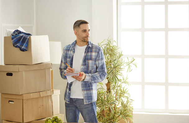 Hombre guapo con cajas en el nuevo apartamento después de mudarse - Foto, Imagen