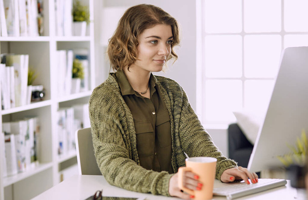 Молодая женщина, работающая с графическим планшетом в офисе
 - Фото, изображение