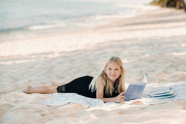 a little girl lies and enjoys the tropical beach of Le Morne in Mauritius.A girl reads a book on a beach in Mauritius. - Φωτογραφία, εικόνα