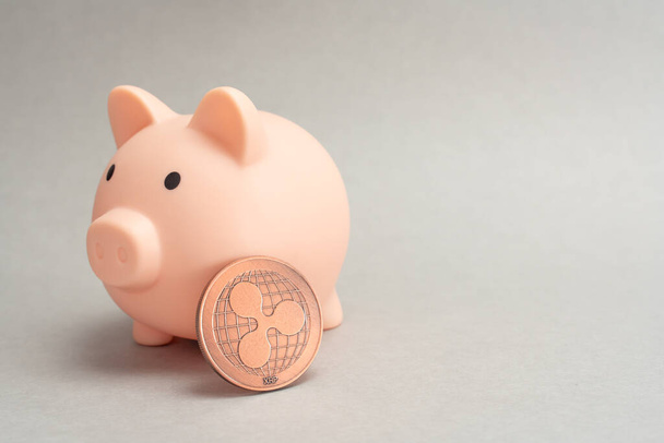 Piggy bank for coins. Ripple holding concept. Cryptocurrency saving symbol. Money box on a gray background. Copy space. - Photo, image