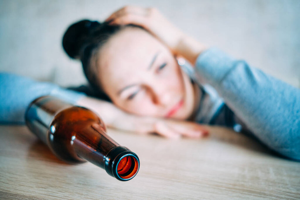 Una mujer borracha se apoyó en la mesa junto a la botella. De cerca.
. - Foto, Imagen