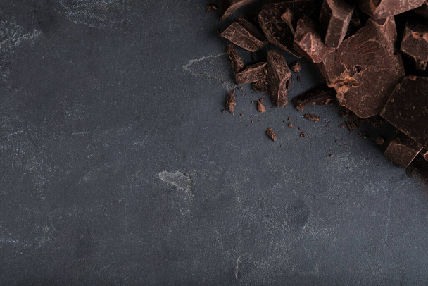 Pieces of tasty dark chocolate on grey table, top view. Space for text - Photo, image