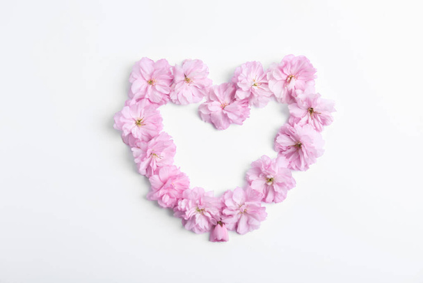 Heart made with sakura blossom on white background, top view. Japanese cherry - Foto, Bild