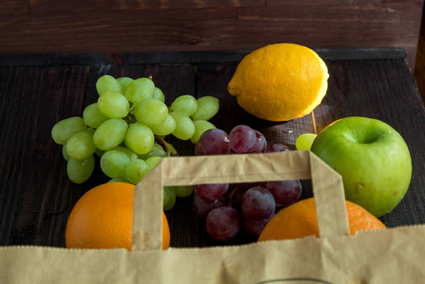 frutas em um saco de papel. laranja, limão, maçã, toranja, uvas. amigo do ambiente. vegetarianismo
 - Foto, Imagem