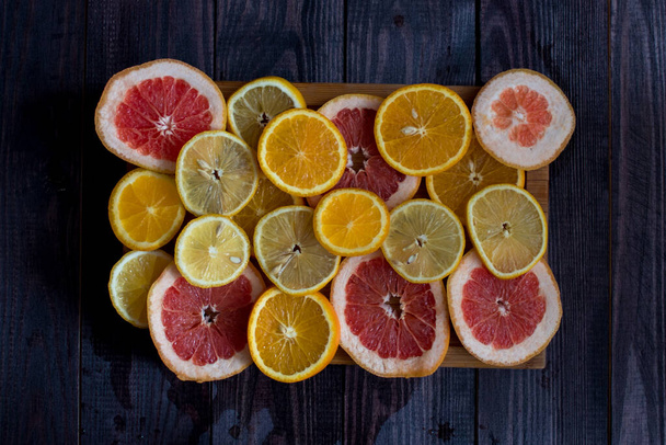 sliced citrus fruits laid out on a wooden background. orange, lemon, grapefruit. top view - Photo, image