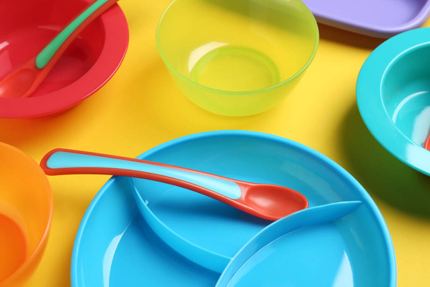 Set of colorful plastic dishware on yellow background. Serving baby food - Zdjęcie, obraz