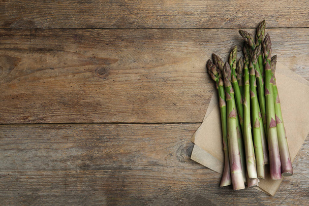 Fresh raw asparagus on wooden table, flat lay. Space for text - 写真・画像