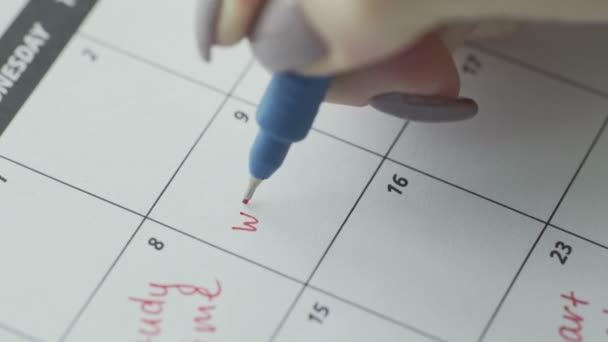 女性の手はカレンダーの単語の仕事に赤いペンで書く - 映像、動画