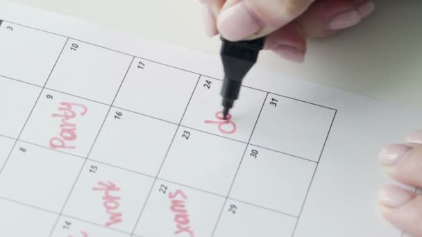 Womans χέρι γραφής με κόκκινο τσόχινο στυλό στο ημερολόγιο λέξη ΗΜΕΡΟΜΗΝΙΑ - Πλάνα, βίντεο