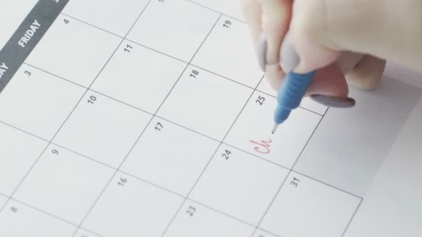 女性の手は、カレンダーの単語クリスマスに赤いペンで書く - 映像、動画