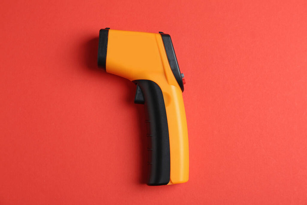 Modern non-contact infrared thermometer on red background, top view - Foto, Bild