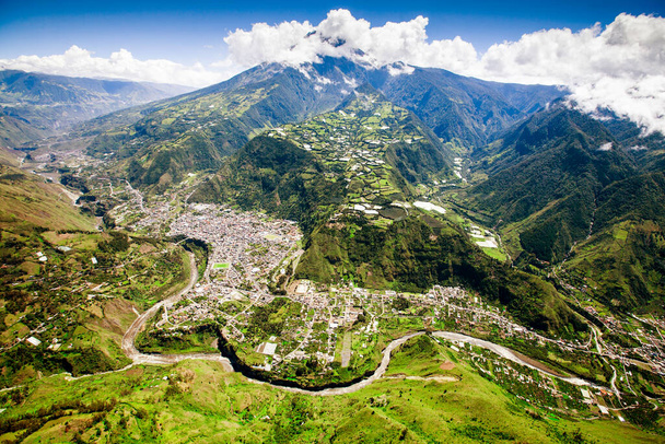 aerial shot of banos de agua santa north to south tungurahua volcano in the background and pastaza river in foreground - Фото, зображення